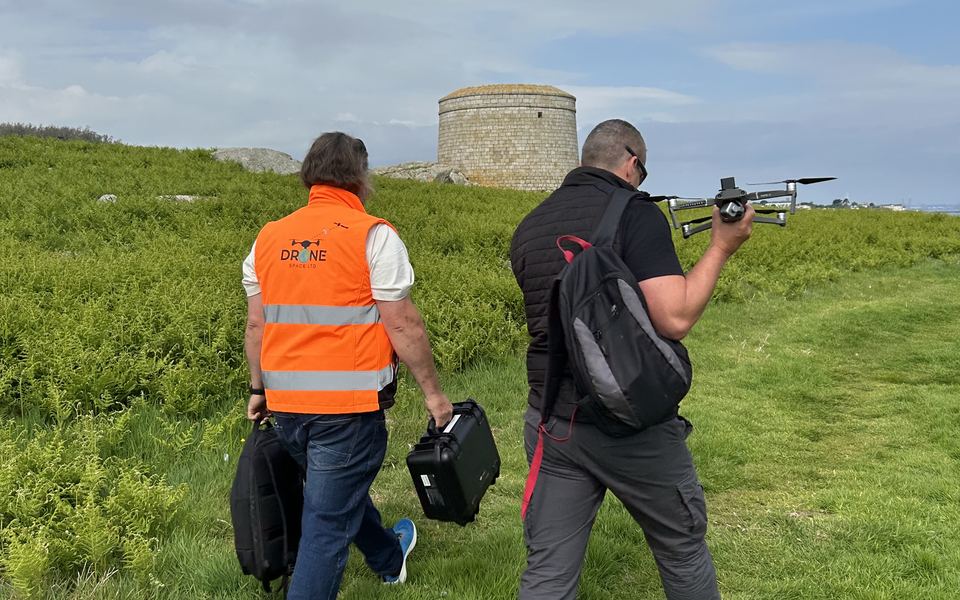 A drone team in high-visibility jackets carrying kit across Dalkey Island
