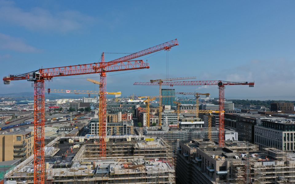The Dublin skyline from the air, with tower cranes over a construction site