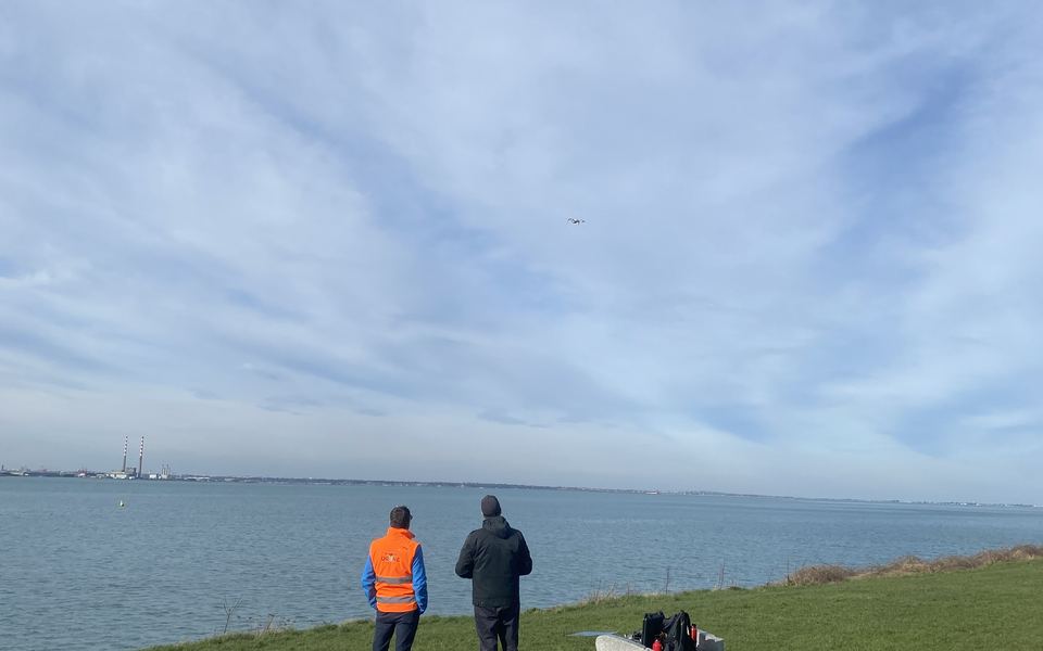 Two people on a coastal headland flying a drone during a training day